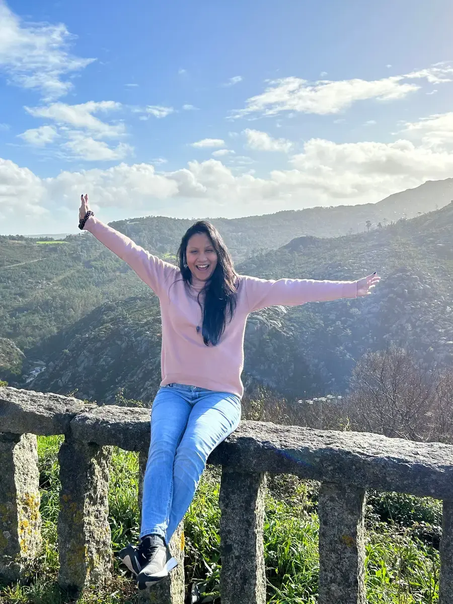 Maryana Morgado sonriendo con los brazos abiertos en un mirador de montaña